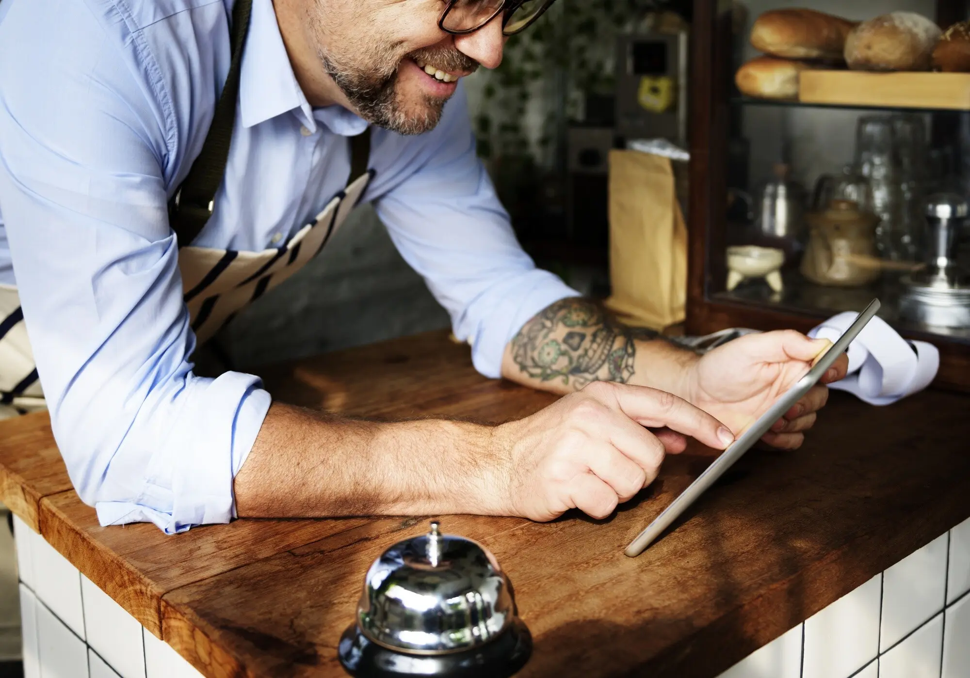 Tätowierter Mann, der in einer Bäckerei ein digitales Tablet benutzt