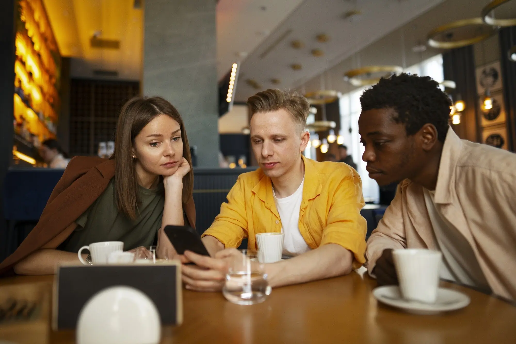 Eine Gruppe von Freunden schaut sich gemeinsam die Speisekarte in einem Restaurant an.